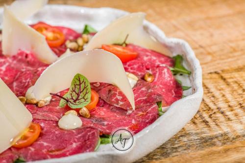a plate of food with meat and tomatoes on a table at ANTICA RESIDENZA TOSCANA in Dumbrăviţa