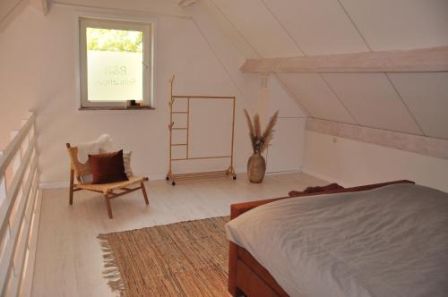 1 dormitorio con cama, ventana y silla en B&B Sonnehuys en Nieuwland