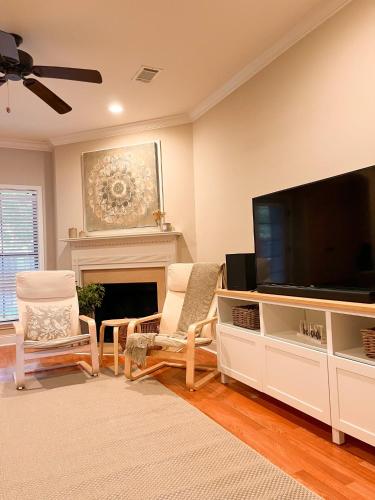 a living room with a flat screen tv and two chairs at Lovely Townhouse! in Auburn