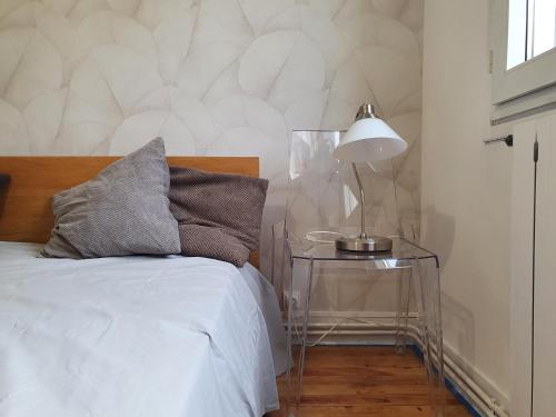 a bedroom with a bed and a table with a lamp at Maison confortable, terrasse et jardin à Amiens in Amiens