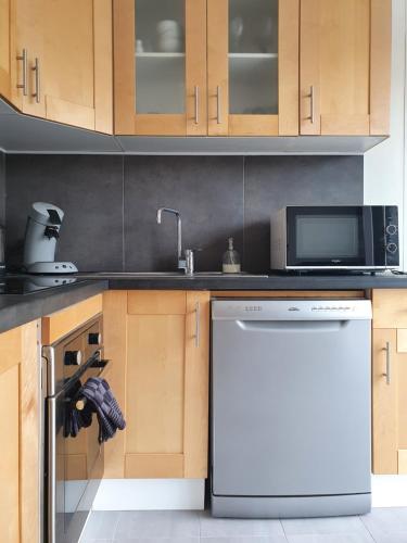 a kitchen with a white dishwasher and a microwave at Maison confortable, terrasse et jardin à Amiens in Amiens