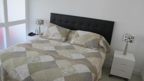 een slaapkamer met een bed met een deken en kussens bij Green Park Hermosos Apartamentos Vista al Lago in Punta del Este