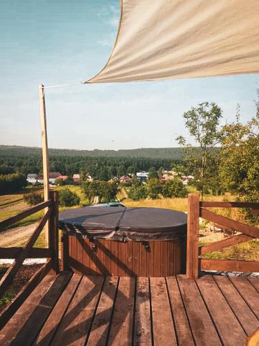 a hot tub sitting on top of a wooden deck at Jurty z widokiem, prywatna balia- DZIKOLAS GLAMPING in Krasnobród