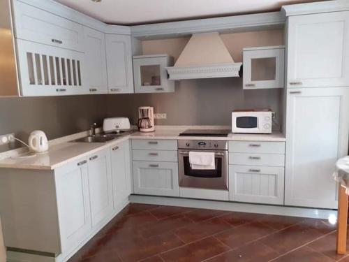 cocina con armarios blancos y fogones en Appartement avec jardin en Roquebrune-Cap-Martin