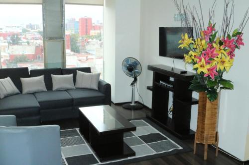 a living room with a couch and a vase of flowers at Puerta Alameda Suites México in Mexico City