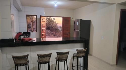 eine Küche mit einer Theke mit Stühlen und einem Kühlschrank in der Unterkunft Shambala centro de São Tomé das letras in São Thomé das Letras