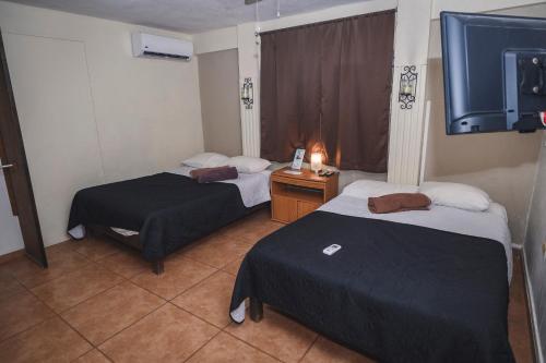 a hotel room with two beds and a tv at Departamento CENTRICO, Tv smart, minisplit nuevo, wifi 100 mb, cocina, lavadora, asador, parking, letra i in Ciudad Valles