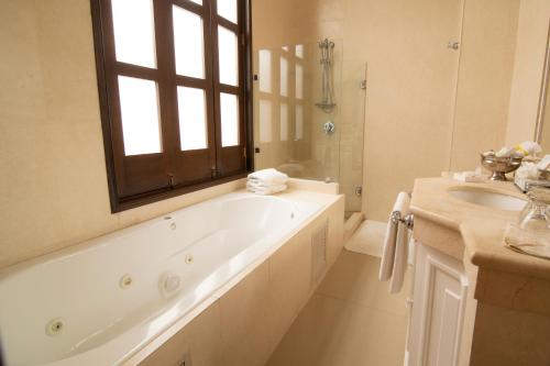 a white bathroom with a tub and a sink at Palacio Borghese Hotel Boutique - Adults Only in Oaxaca City