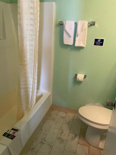a bathroom with a toilet and a shower with towels at Southwind Inn in Port Isabel