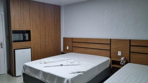 1 dormitorio con 2 camas y armarios de madera en ARARAS Apart Hotel - CTC, en Caldas Novas