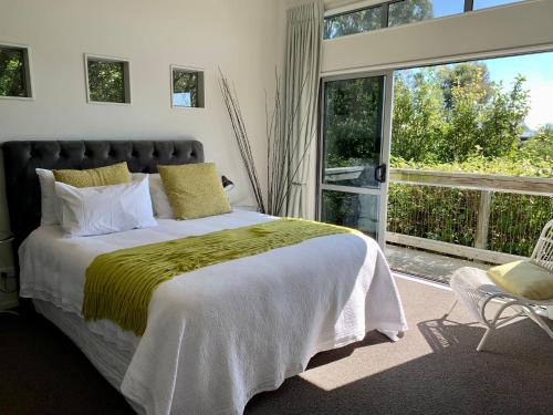 a bedroom with a bed and a large window at Lacebark Treetops Cottage: 2 bed/2en-suite option in Havelock North