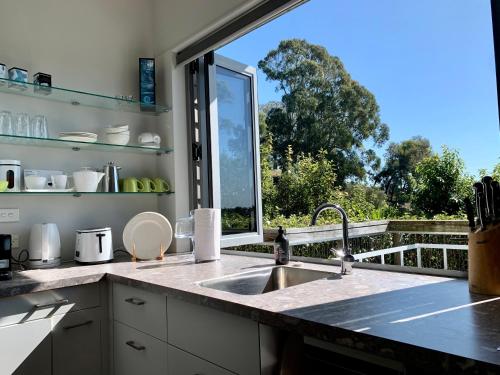 a kitchen with a sink and a large window at Lacebark Treetops Cottage: 2 bed/2en-suite option in Havelock North