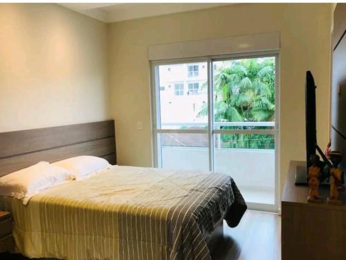 a bedroom with a bed and a large window at Apartamento Executivo - No melhor lugar do América in Joinville