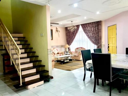 ein Esszimmer und ein Wohnzimmer mit einem Tisch und einer Treppe in der Unterkunft Homestay Rumah Singgah in Jitra
