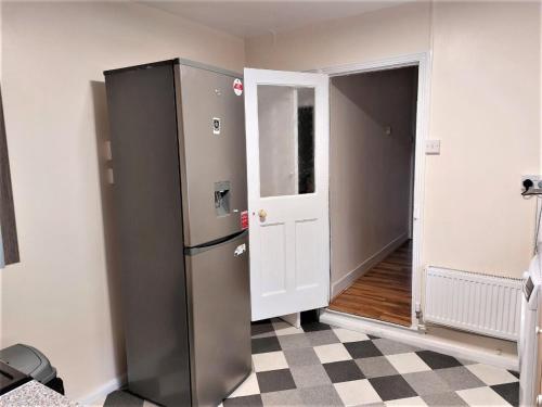 a kitchen with a refrigerator next to a door at Cheerful 3 Bedroom Home in Greater London in London