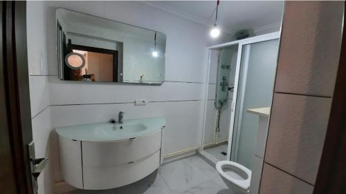 a white bathroom with a sink and a mirror at شقة الكرنيش in Nador