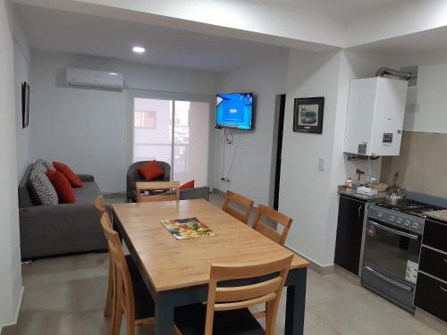 cocina y sala de estar con mesa de madera, cocina y sofá en Departamentos Giovanni en Salta