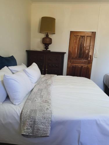 a bedroom with a bed with white sheets and a lamp at Mzila Forest Creek in Maanhaarrand
