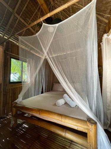 a bed in a room with a mosquito net at La Tortue Diving Resort Dauin in Dauin