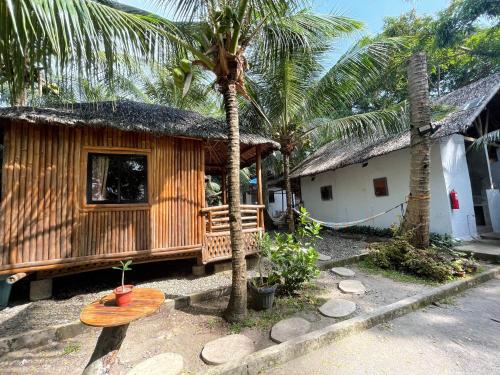 a wooden house with a bench and palm trees at La Tortue Diving Resort Dauin in Dauin