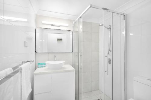a white bathroom with a sink and a shower at Amaroo At Trinity in Trinity Beach