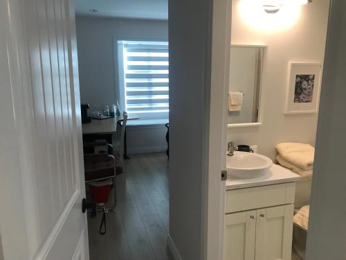 La salle de bains blanche est pourvue d'un lavabo et d'un miroir. dans l'établissement Holland Villa Vancouver, à New Westminster