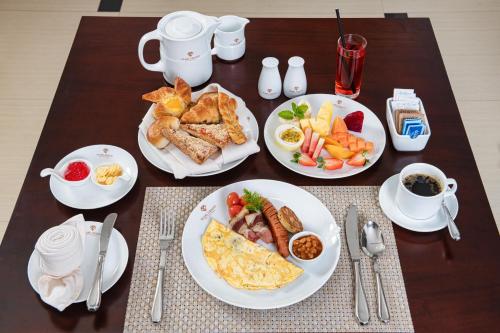 a table with plates of breakfast food on it at Pearl Grand By Rathna in Colombo