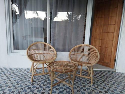 twee stoelen en een tafel voor een raam bij Villa Kebun Prambanan in Randugunting