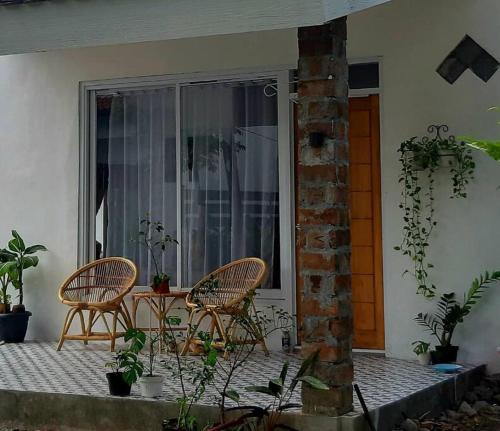 twee stoelen en een tafel op een veranda met planten bij Villa Kebun Prambanan in Randugunting