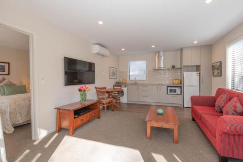 a living room with a red couch and a kitchen at 2 Oaks Cottage Clyde in Clyde