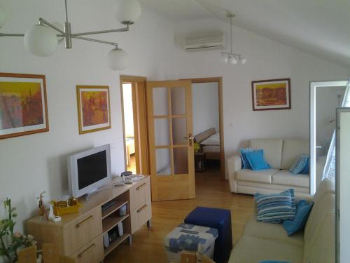 ein Wohnzimmer mit einem Sofa und einem TV in der Unterkunft Apartments by the sea Sumartin, Brac - 11651 in Sumartin