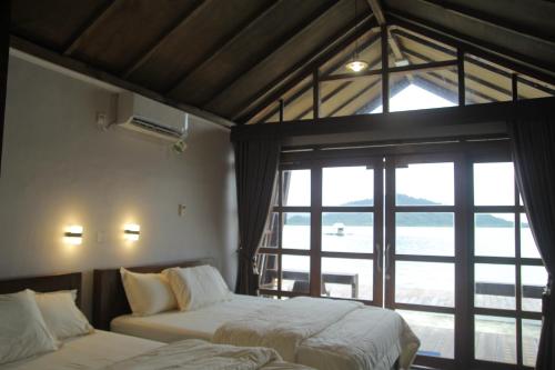 1 dormitorio con 2 camas y ventana grande en Teras Pahawang, en Sukojayo