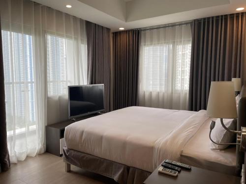 a bedroom with a bed and a tv and windows at The Residences at BCCT in Manila