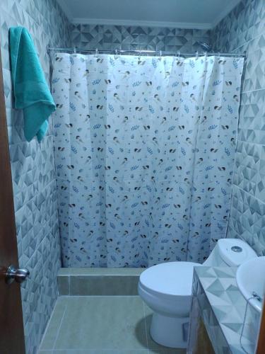 a bathroom with a shower curtain with a toilet at El Nido del Colibri in Guanaqueros