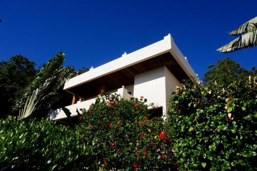 a white building with red flowers in front of trees at KohTao Studios Sunset in Koh Tao