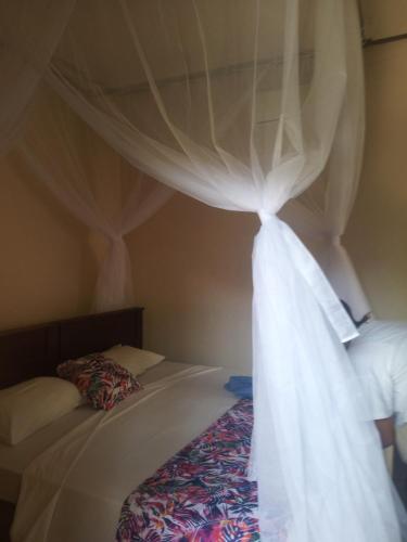 a bedroom with two beds with white curtains at Mango Moon in Pemuteran