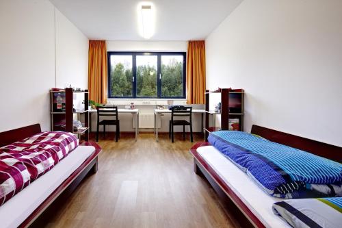 1 Schlafzimmer mit 2 Betten, einem Schreibtisch und einem Fenster in der Unterkunft Alm 34 mit 24 Stunden Self Check in in Saalfelden am Steinernen Meer