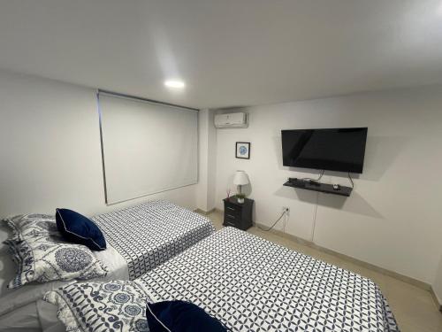 a bedroom with two beds and a flat screen tv at Ingenio Park 83 - Apartahotel in Cali