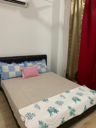 a bed with a blanket and pillows on it at Apartment Uno teratak kasih in Sandakan