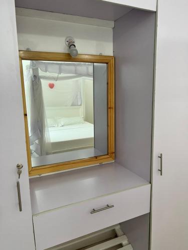 a mirror on a cabinet with a bed in it at Kijani Paradise Malindi in Malindi