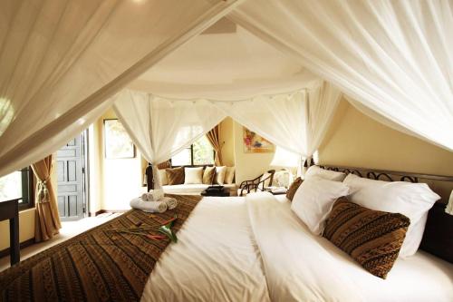 a bedroom with a large white bed with curtains at Villa Khao Phaengma in Wang Nam Khieo