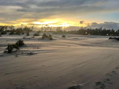 a sunset on a beach with footprints in the sand at Kijani Paradise Malindi in Malindi