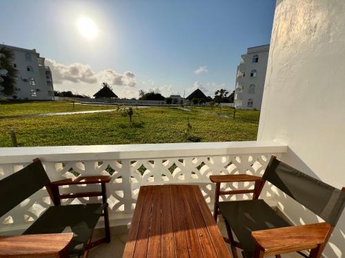 a wooden table and chairs on a balcony with a field at Kijani Paradise Malindi in Malindi