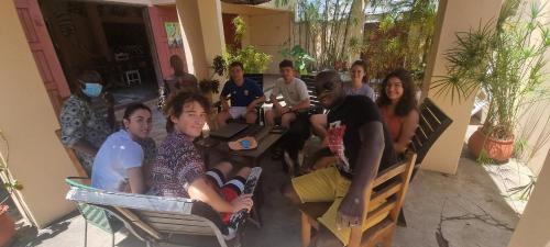 un grupo de personas sentadas en mesas en una habitación en La Guesthouse Étoile en Cotonú