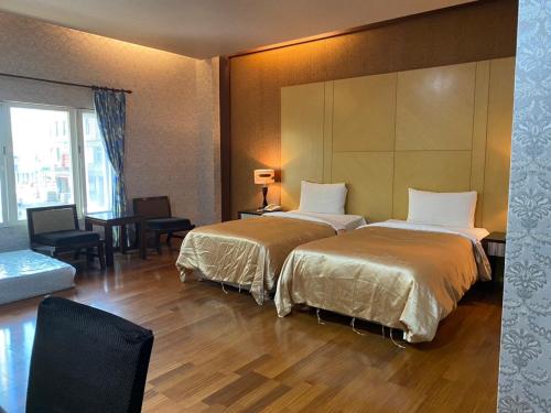 a hotel room with two beds and a table at Treasure Island Motel - Fengshan in Kaohsiung