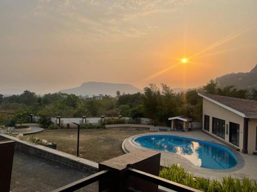 Villa at Lonavala - SaGa Montana (Hill View) في لونافالا: حديقة خلفية مع حمام سباحة ومنزل