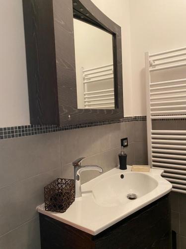 W łazience znajduje się biała umywalka i lustro. w obiekcie Chirone Room w mieście Mondello