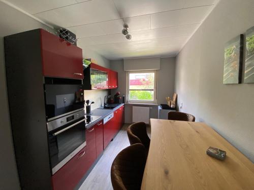 布勞恩拉格的住宿－Brockenblick，厨房配有红色橱柜和木桌