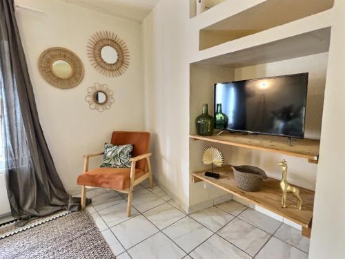 a living room with a tv and a chair at L'abeille - Centre - Parking gratuit in Bourg-de-Péage