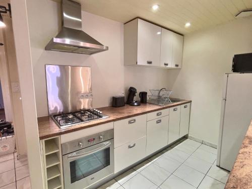 a kitchen with white cabinets and a stove top oven at L'abeille - Centre - Parking gratuit in Bourg-de-Péage